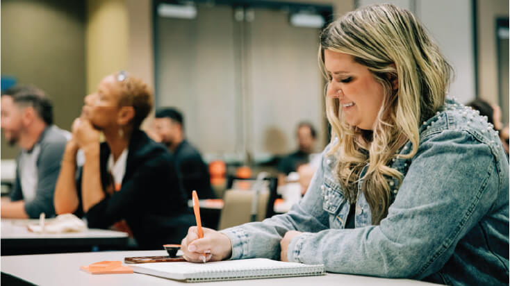 a woman taking notes in a classroom setting